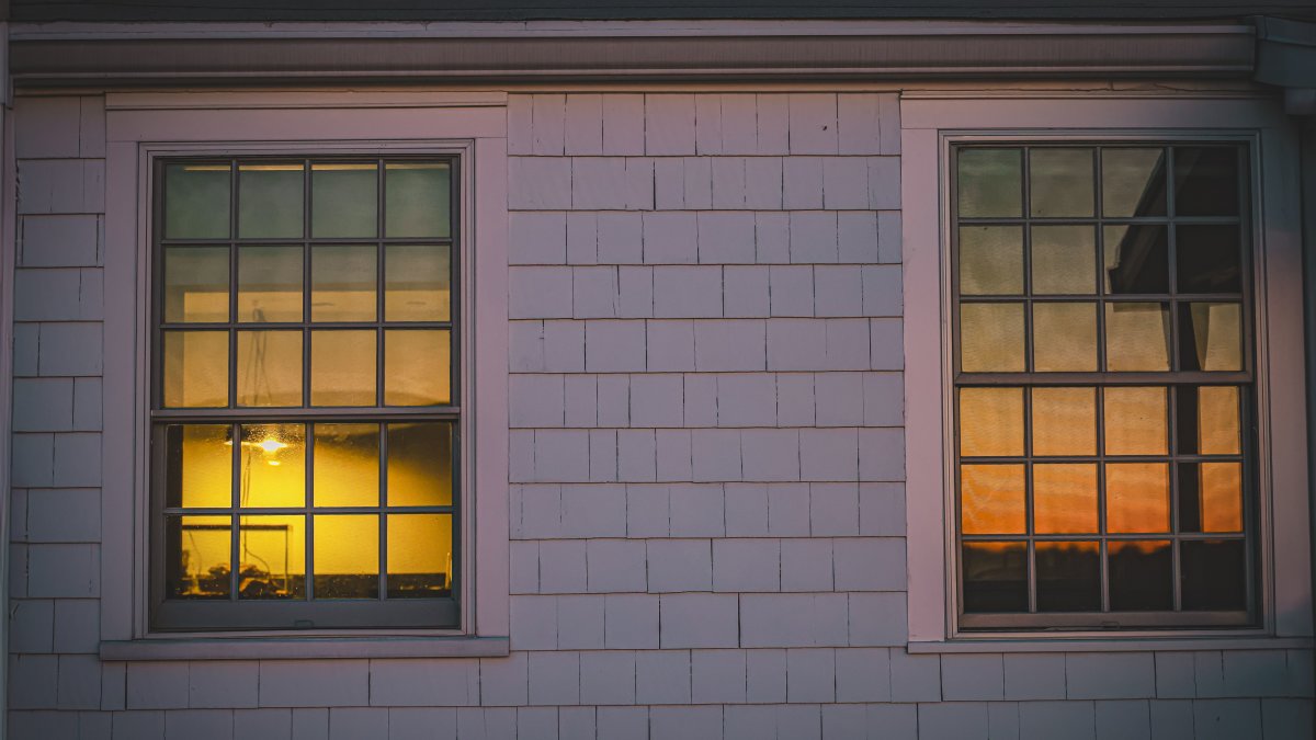 House windows reflecting indoor lighting with vibrant twilight sky