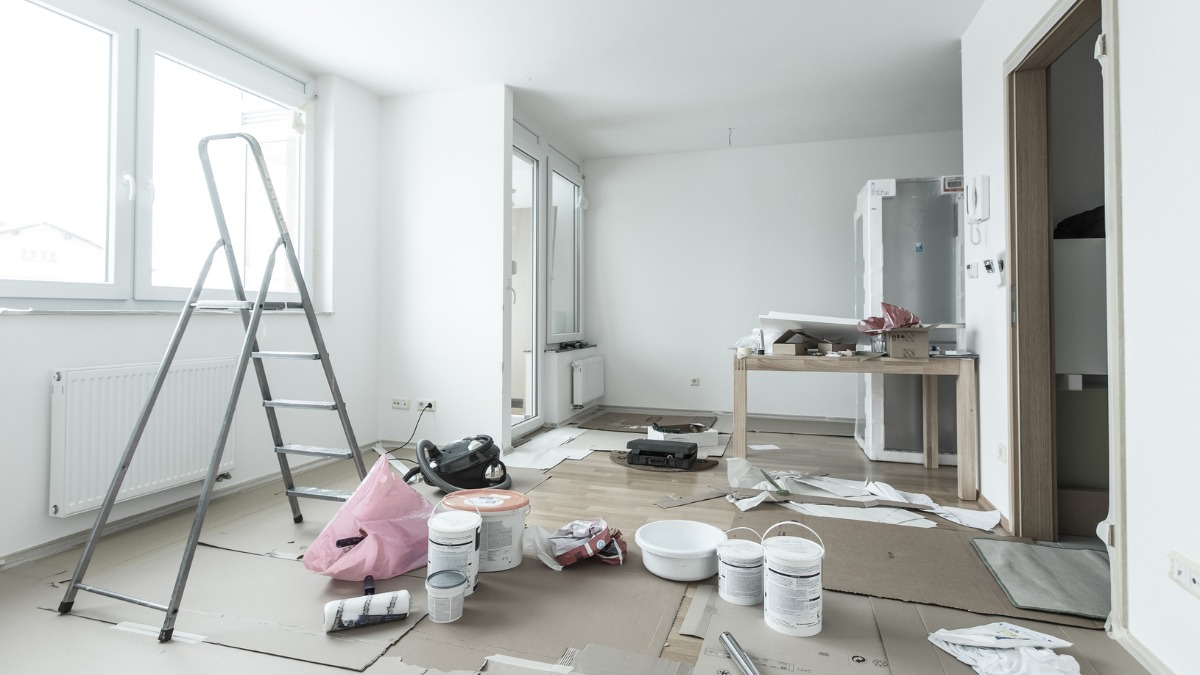 Messy apartment interior undergoing renovation with paint buckets